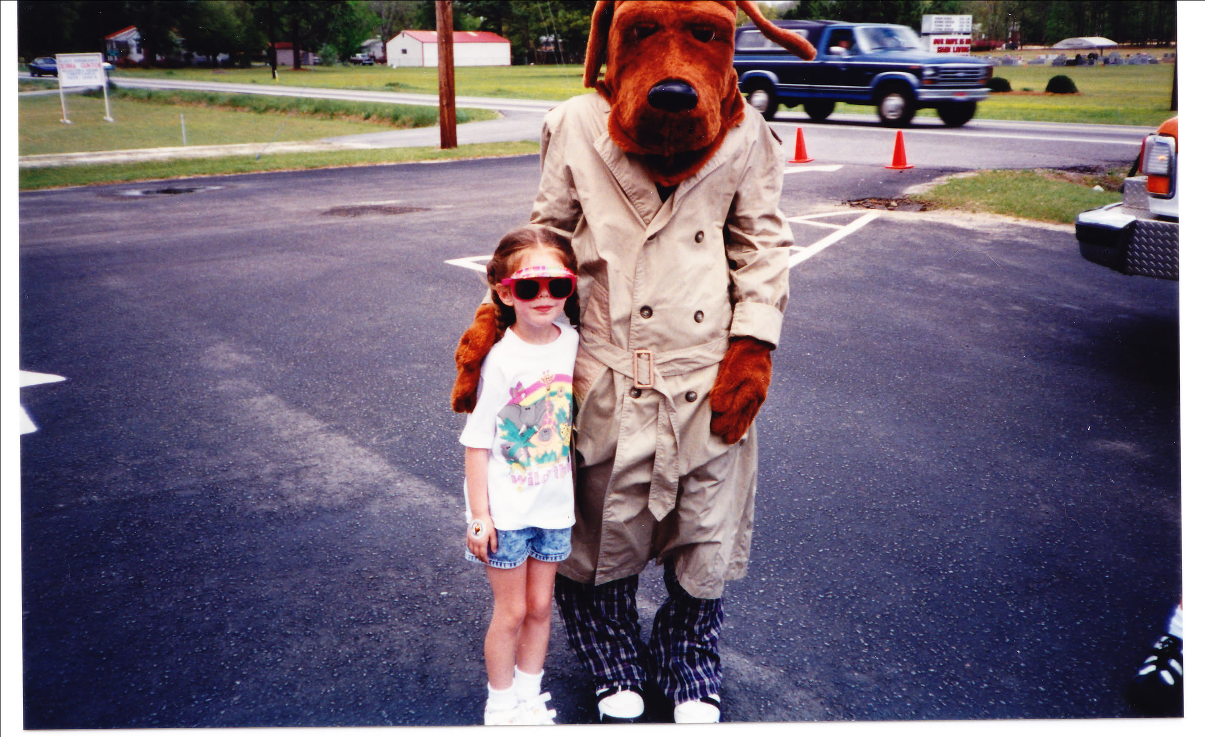 Photo of four-ish year old me with someone in a McGruff the Crime Dog suit. I'm wearing a truly spectacular sunglasses/visor two in one