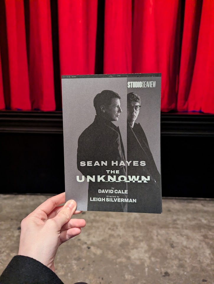 Holding my playbill for The Unknown starring Sean Hayes in front of the curtain of the stage. POV from my front row center seat.