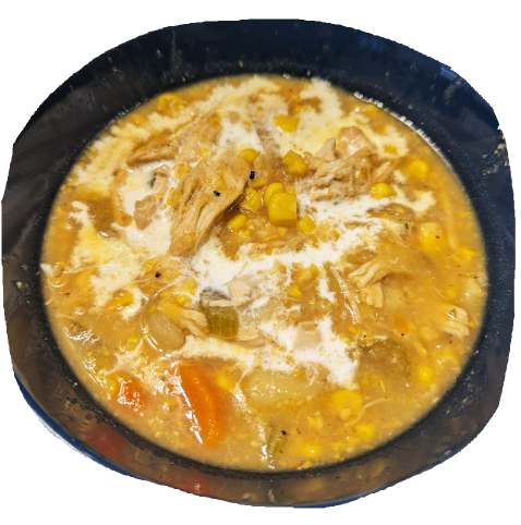 Chicken corn chowder in a dark blue bowl with some cream splashed in.